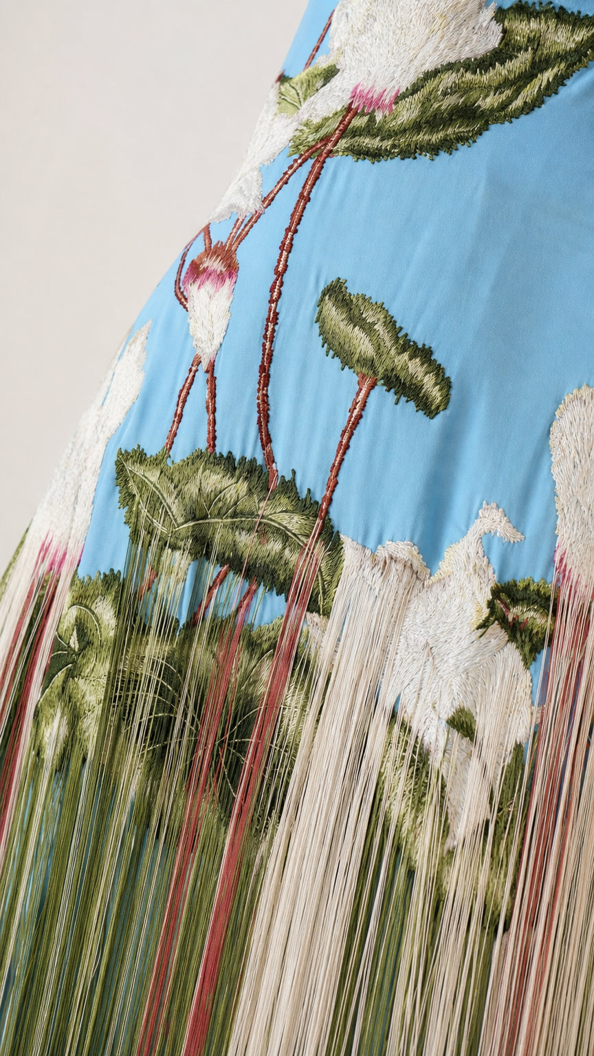 Close-up detail of botanical embroidery and fine fringe on the dress